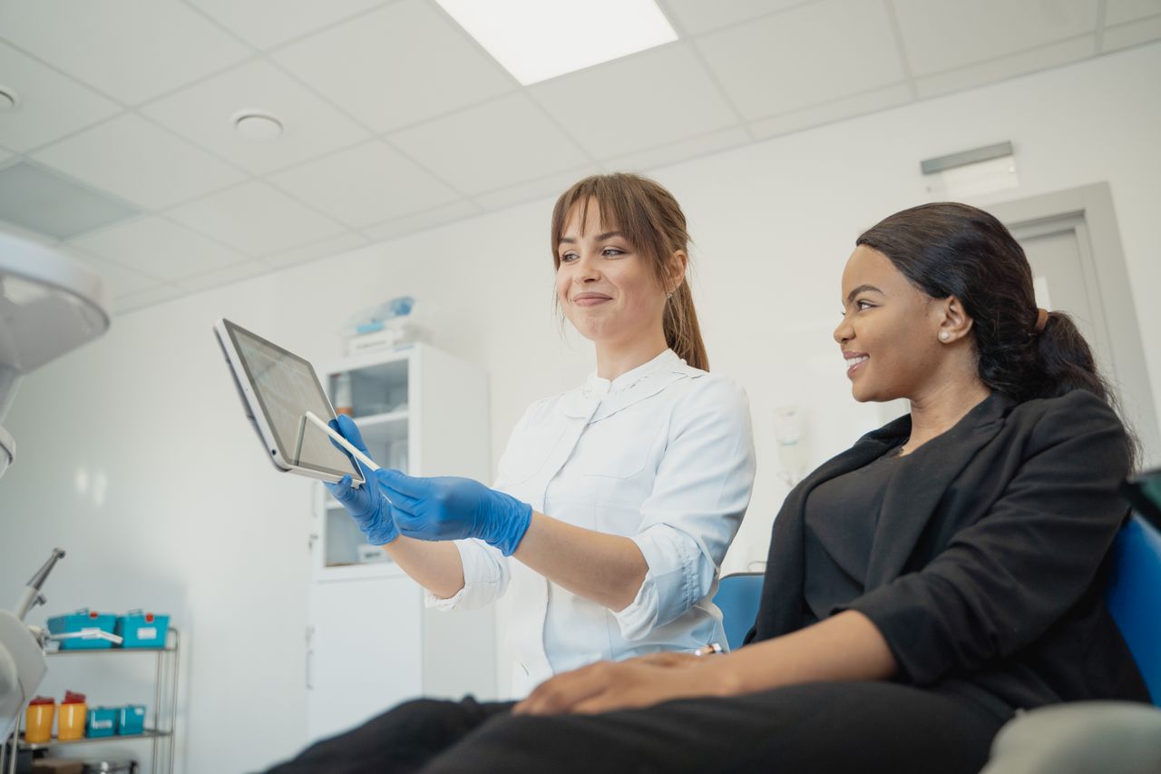 about-us-02 Dentist and patient discussing treatment plan using a tablet in a modern clinic setting.