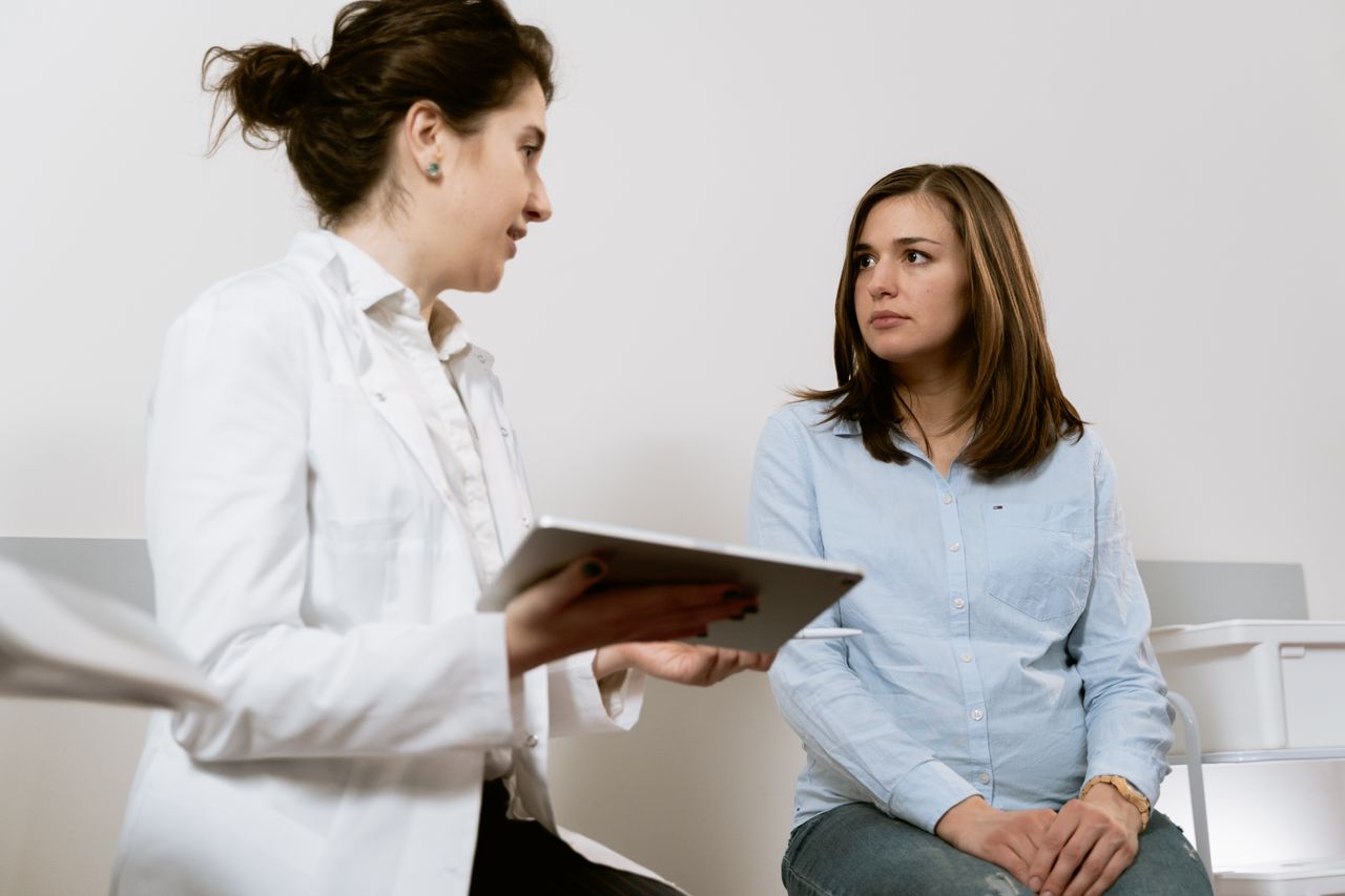 about-us-01 A doctor consults with a pregnant patient discussing healthcare options in a medical facility.